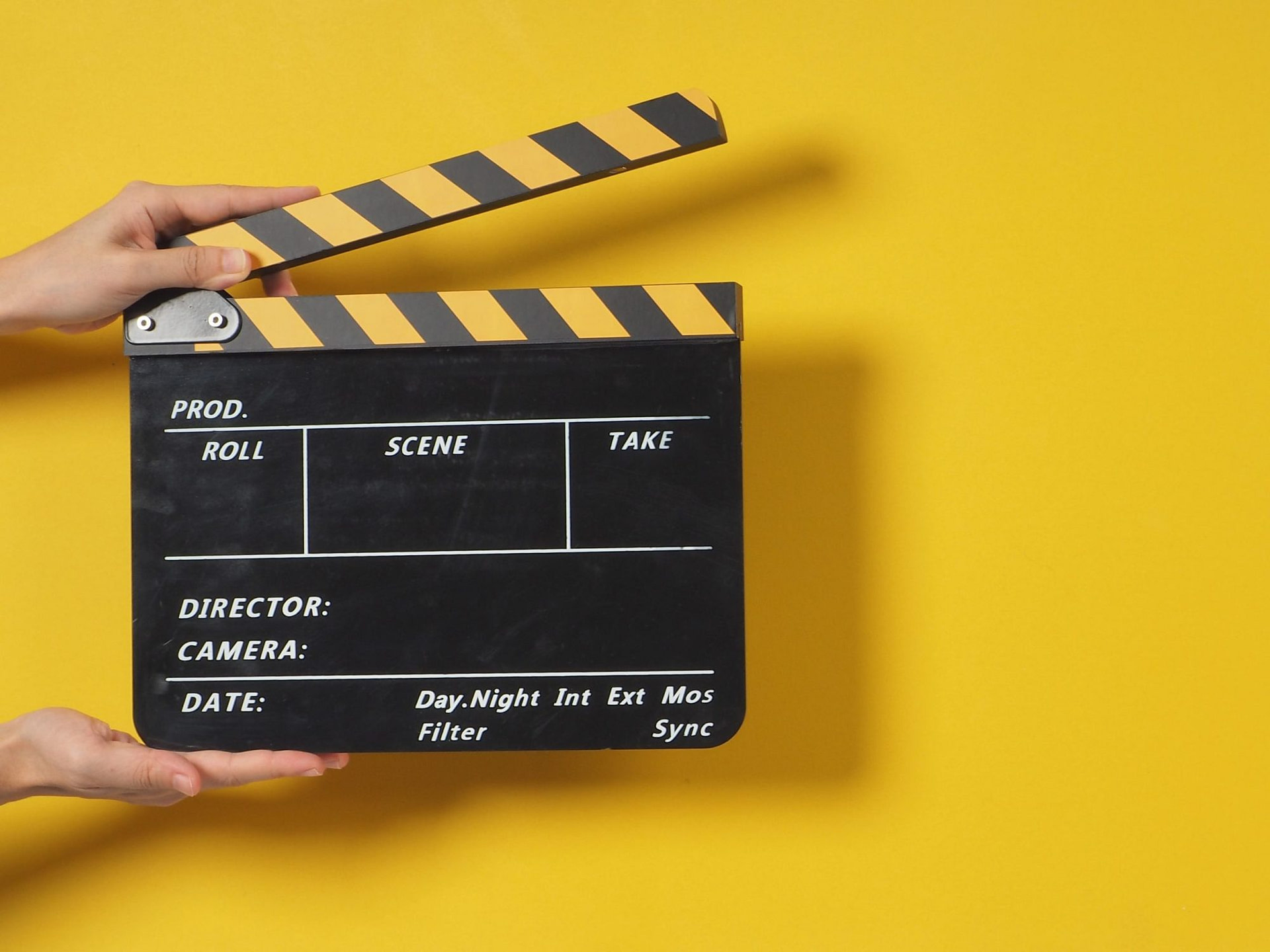 Hand is holding clapper board or movie slate.It is used in video production and film industry on yellow background.